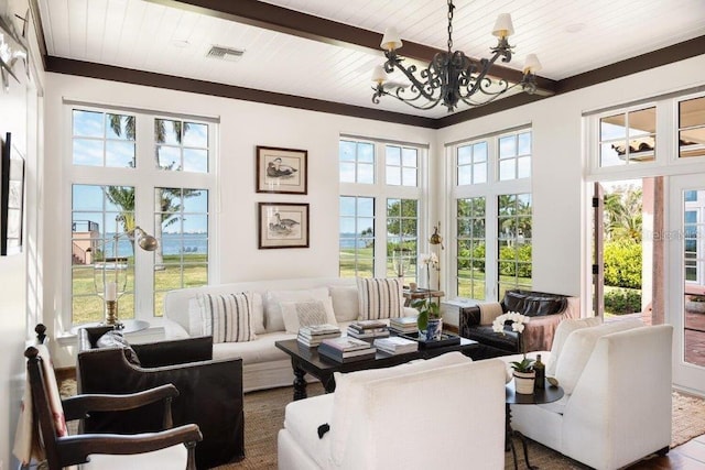 sunroom / solarium with french doors, a healthy amount of sunlight, beam ceiling, and a chandelier