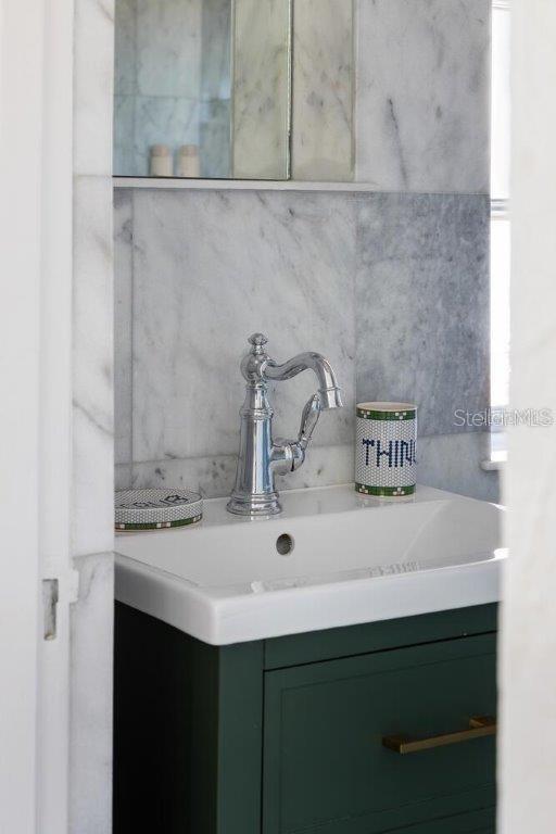 interior details featuring vanity and tasteful backsplash