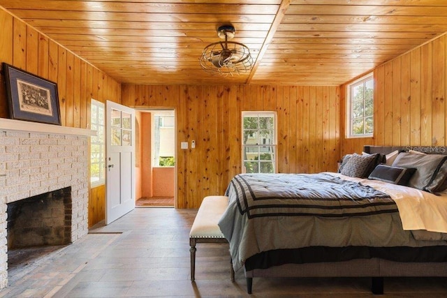 bedroom featuring wood ceiling, a brick fireplace, hardwood / wood-style floors, and multiple windows