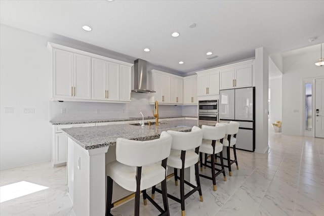 kitchen with white cabinetry, wall chimney exhaust hood, light stone counters, backsplash, and white fridge