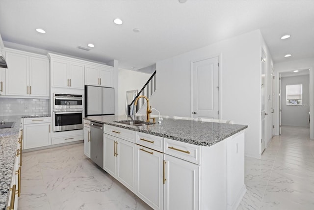 kitchen with stone counters, a center island with sink, and appliances with stainless steel finishes