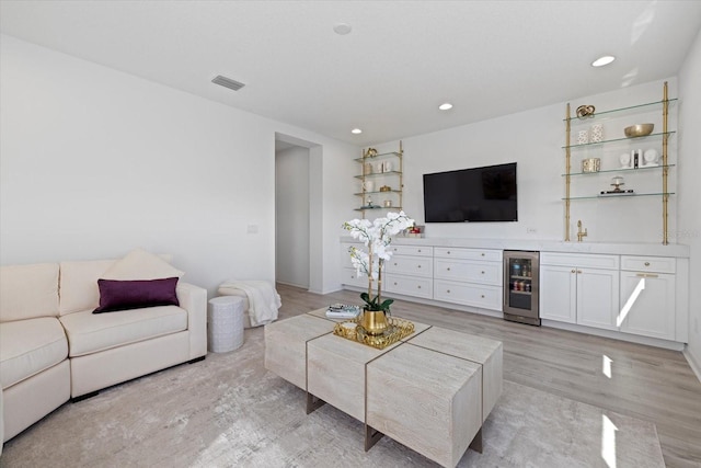 living room with beverage cooler, indoor wet bar, and light hardwood / wood-style floors