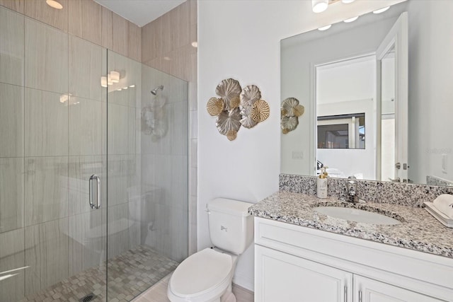 bathroom with a shower with door, vanity, and toilet