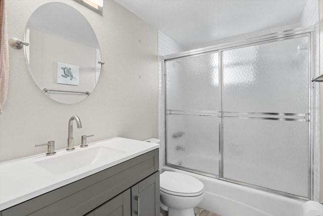 full bathroom featuring vanity, toilet, and bath / shower combo with glass door