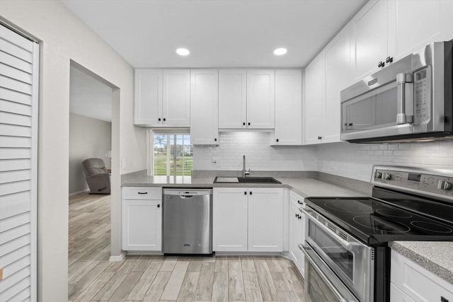 kitchen with light wood-type flooring, white cabinetry, sink, and appliances with stainless steel finishes