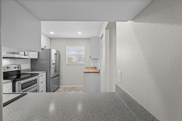 kitchen with tasteful backsplash, white cabinets, and stainless steel appliances