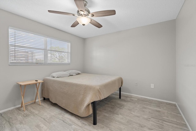 bedroom with ceiling fan, light wood-type flooring, and a textured ceiling