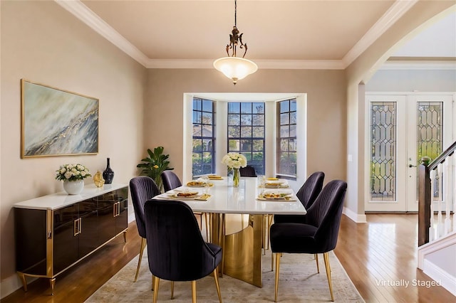 dining space with ornamental molding and light hardwood / wood-style flooring