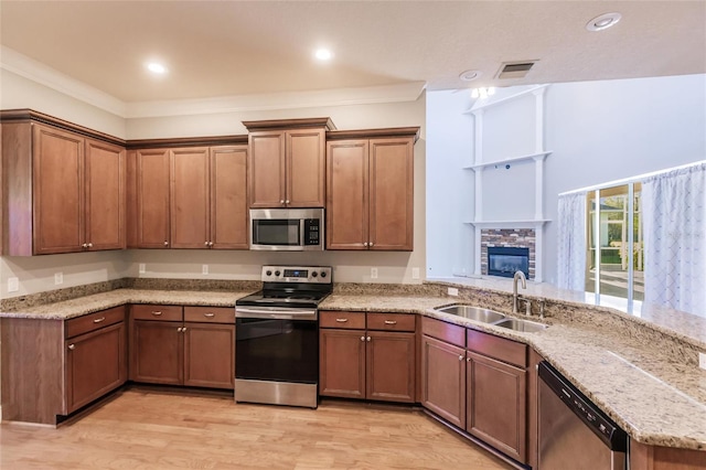 kitchen featuring light stone countertops, appliances with stainless steel finishes, crown molding, sink, and light hardwood / wood-style flooring