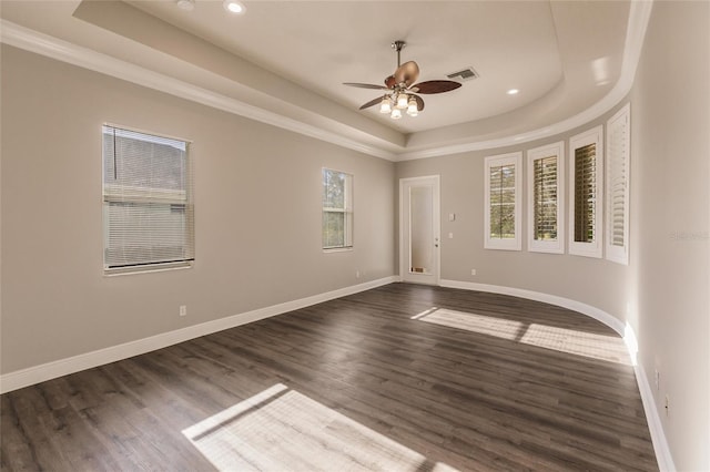 spare room featuring a raised ceiling, ceiling fan, dark wood-type flooring, and ornamental molding