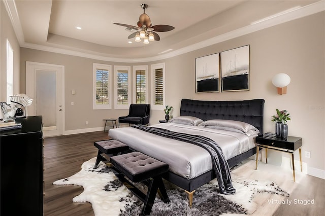 bedroom featuring ceiling fan, dark hardwood / wood-style flooring, ornamental molding, and a tray ceiling