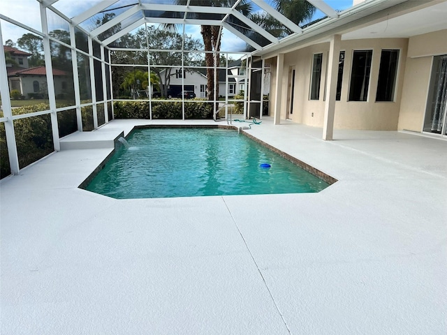 view of swimming pool with pool water feature, glass enclosure, and a patio area