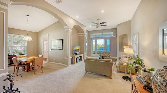 living room featuring light carpet, decorative columns, high vaulted ceiling, and ceiling fan