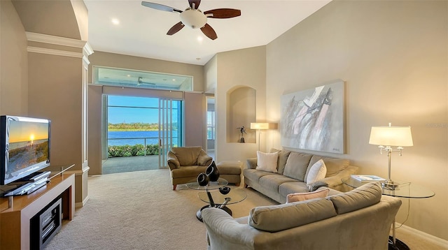 living room featuring ceiling fan, a water view, light colored carpet, and ornamental molding