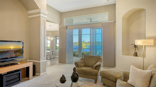 carpeted living room with decorative columns, plenty of natural light, and a water view