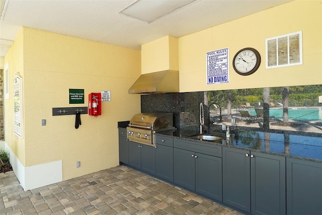 kitchen with dark stone countertops, decorative backsplash, sink, and exhaust hood