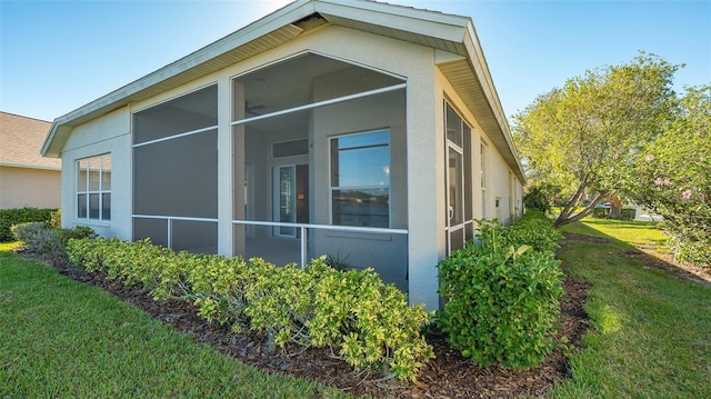 7407 Sea Island Ln, Bradenton, FL 34201 - view of side of home with stucco siding, a sunroom, and a lawn