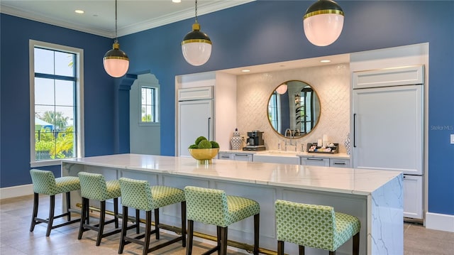 kitchen featuring a kitchen breakfast bar, hanging light fixtures, crown molding, white cabinets, and a large island