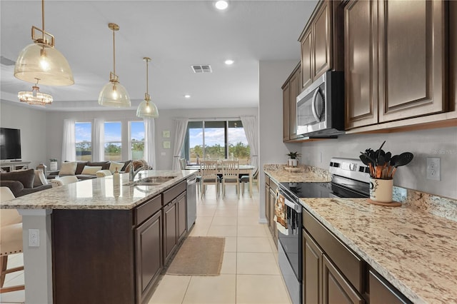 kitchen with sink, light tile patterned floors, dark brown cabinets, a kitchen bar, and stainless steel appliances