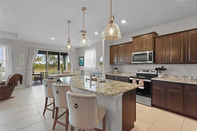 kitchen with sink, a breakfast bar area, an island with sink, decorative light fixtures, and stainless steel appliances