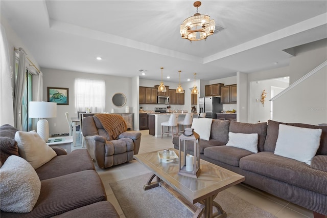 tiled living room featuring a tray ceiling and an inviting chandelier