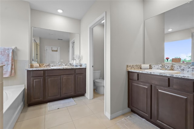 bathroom with tile patterned flooring, vanity, a tub to relax in, and toilet