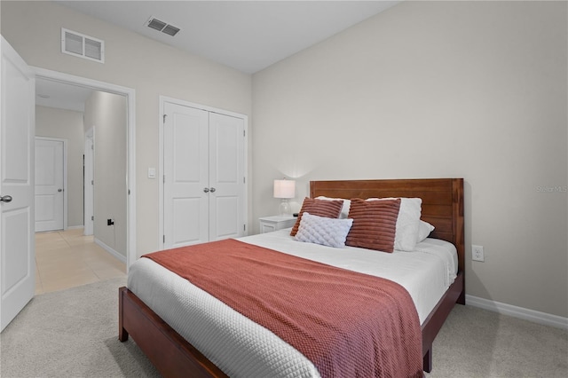 bedroom with a closet, visible vents, light carpet, and baseboards