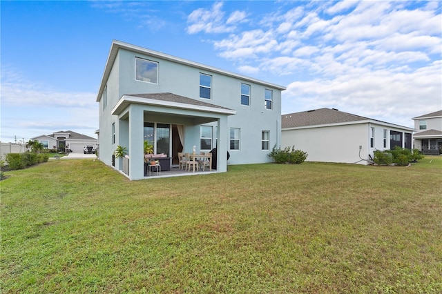 rear view of property featuring a yard, a patio area, and stucco siding