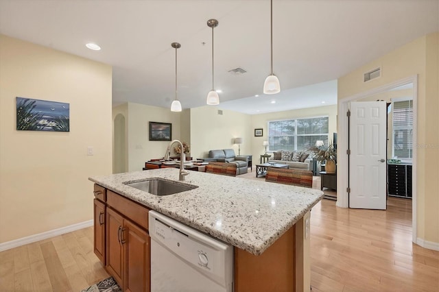 kitchen featuring sink, hanging light fixtures, light hardwood / wood-style flooring, white dishwasher, and a kitchen island with sink