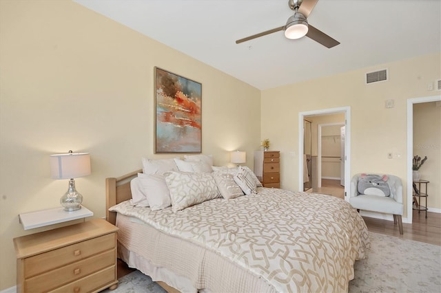 bedroom with a walk in closet, a closet, light hardwood / wood-style flooring, and ceiling fan