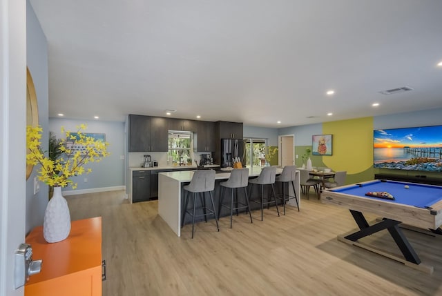 kitchen featuring a kitchen island, pool table, a kitchen breakfast bar, light hardwood / wood-style flooring, and stainless steel refrigerator with ice dispenser