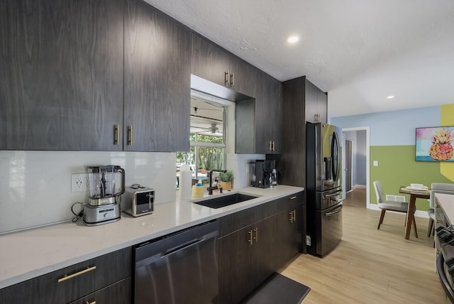 kitchen featuring appliances with stainless steel finishes, light hardwood / wood-style flooring, dark brown cabinetry, and sink