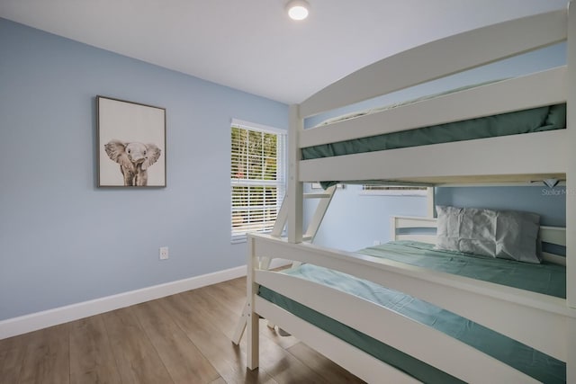 bedroom with wood-type flooring and vaulted ceiling