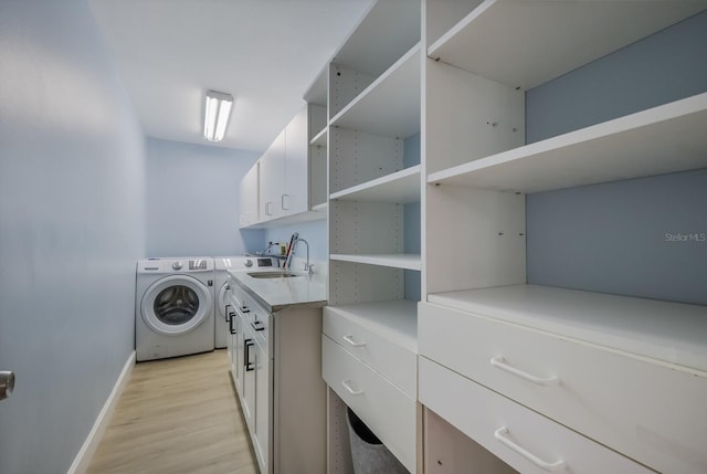 laundry room featuring light hardwood / wood-style floors, washing machine and dryer, sink, and cabinets