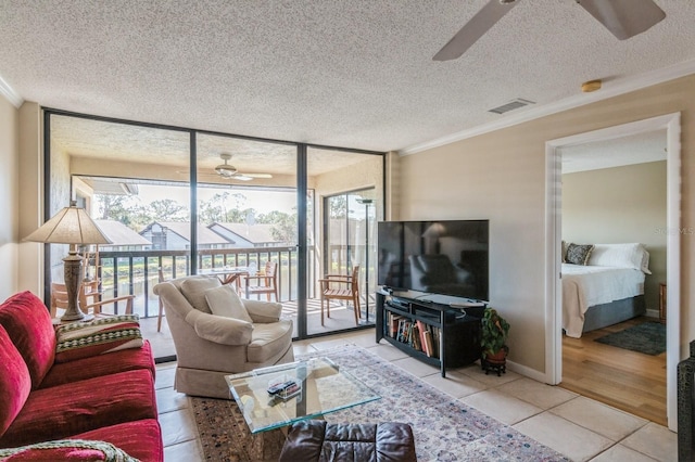 tiled living room featuring ceiling fan, ornamental molding, and a textured ceiling