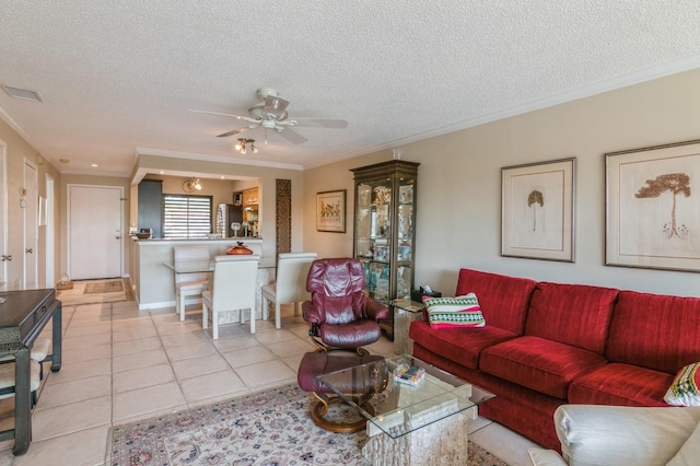 living room featuring light tile patterned floors, a textured ceiling, ceiling fan, and crown molding