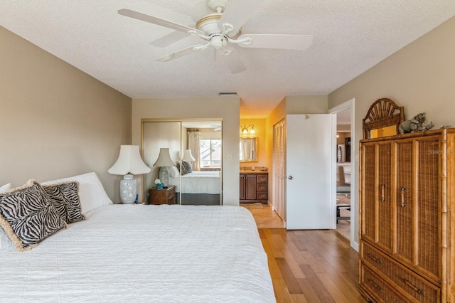 bedroom featuring ensuite bathroom, light hardwood / wood-style floors, a textured ceiling, and ceiling fan