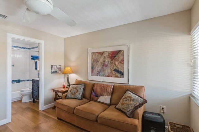 living room featuring ceiling fan, a textured ceiling, and light hardwood / wood-style flooring