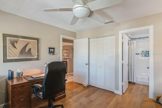 home office featuring a textured ceiling, light hardwood / wood-style floors, and ceiling fan