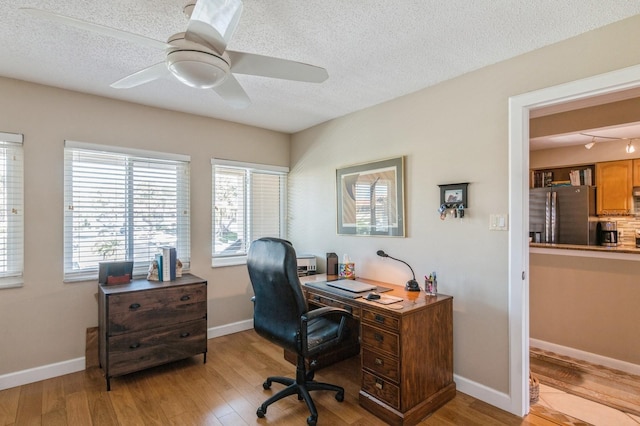 office area featuring ceiling fan, light hardwood / wood-style flooring, and a textured ceiling