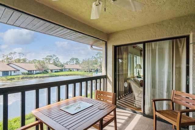 balcony with ceiling fan and a water view