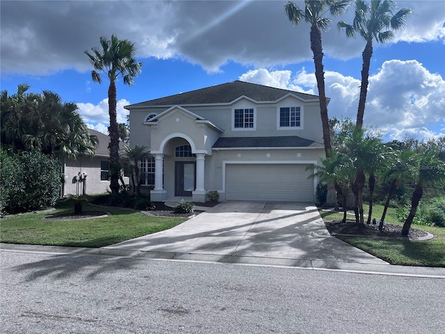 view of front of house featuring driveway, an attached garage, a front yard, and stucco siding