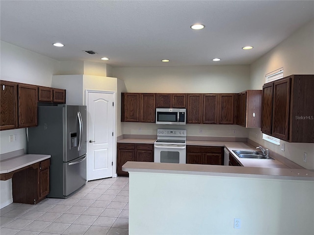 kitchen with light tile patterned flooring, sink, kitchen peninsula, appliances with stainless steel finishes, and dark brown cabinets