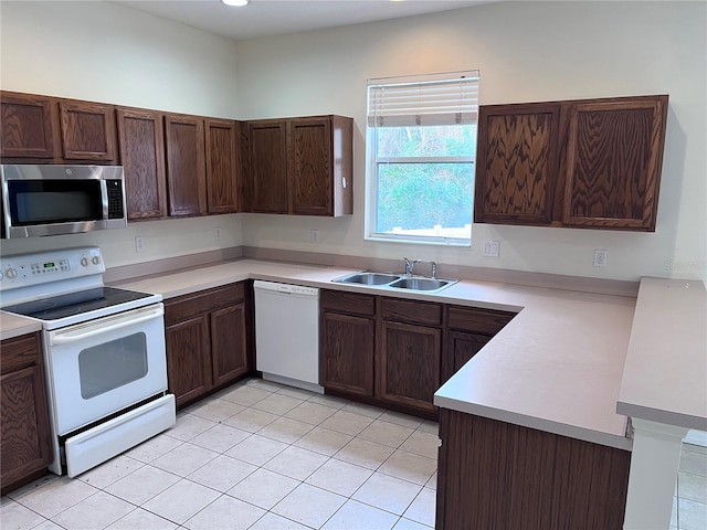 kitchen featuring light tile patterned floors, white appliances, sink, and kitchen peninsula