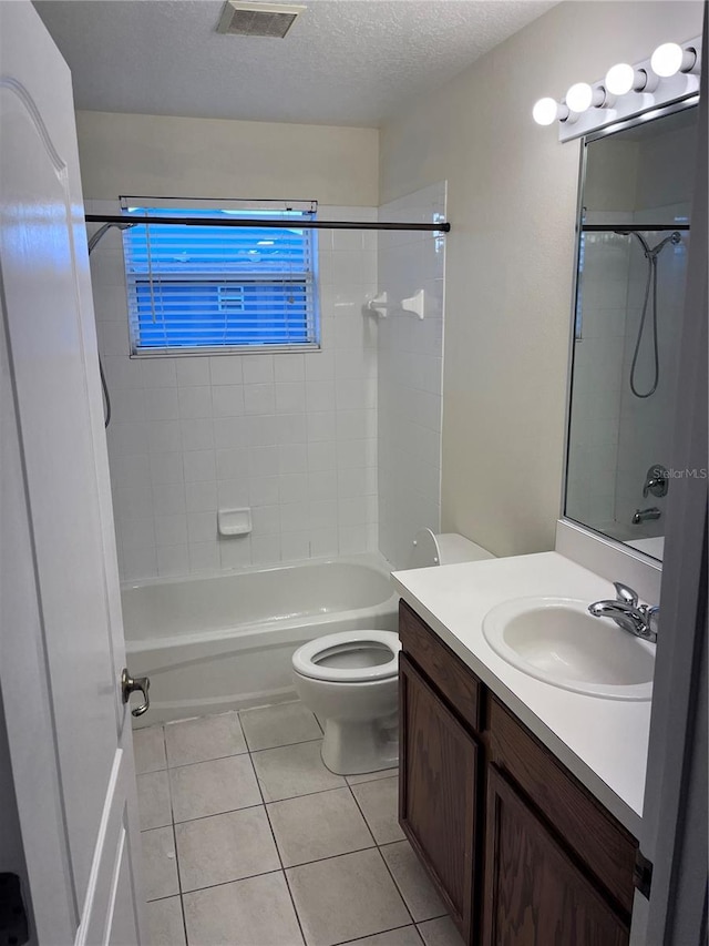 full bathroom featuring tile patterned flooring, a textured ceiling, vanity, toilet, and tiled shower / bath combo