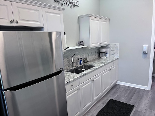 kitchen featuring white cabinets, hardwood / wood-style floors, sink, backsplash, and stainless steel fridge