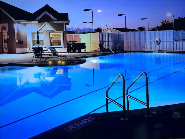 pool at dusk with a patio area