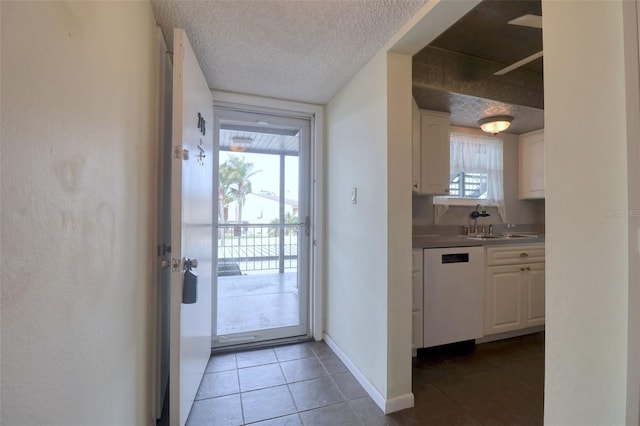 doorway to outside with a wealth of natural light, sink, dark tile patterned floors, and a textured ceiling