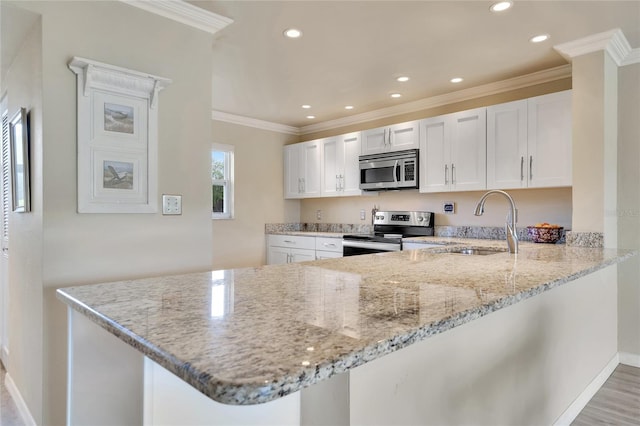 kitchen with kitchen peninsula, appliances with stainless steel finishes, and white cabinetry