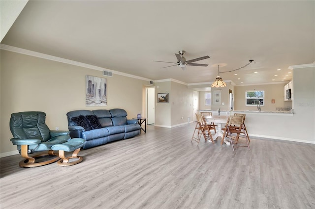 living room with ceiling fan, ornamental molding, and light wood-type flooring